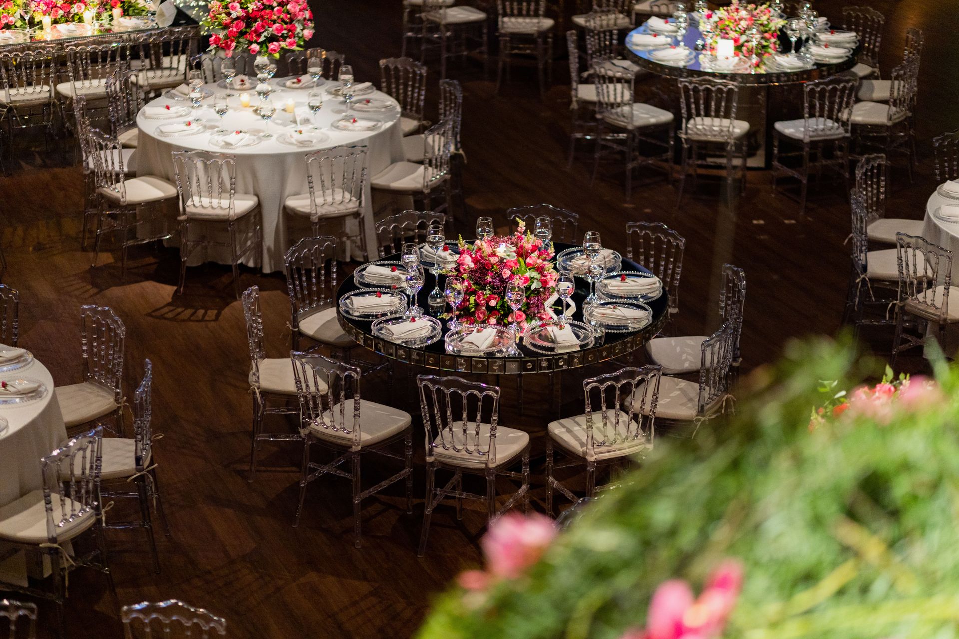 Luxurious wedding reception with round tables and pink floral arrangements.