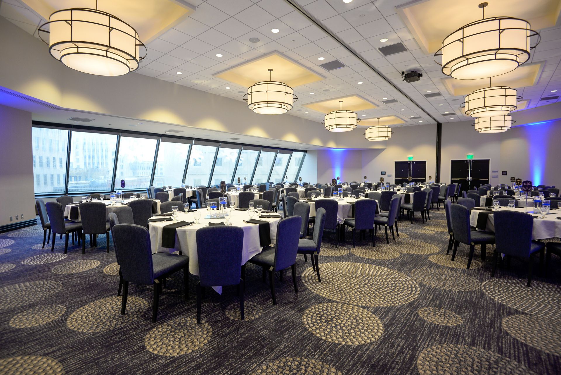 Spacious banquet hall featuring elegant dining tables set for a formal event under modern lighting.